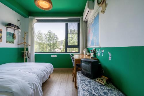 a green room with a bed and a desk with a tv at 闲山民宿 CosyValley Inn in Hangzhou