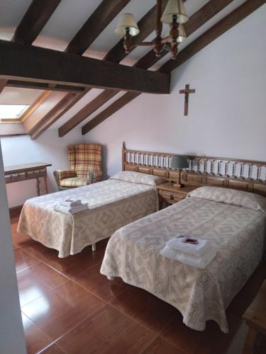a bedroom with two beds and a cross on the wall at Posada San Miguel in RIonansa