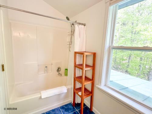 a bathroom with a shower and a wooden shelf next to a window at Shady Lane Retreat in Waitsfield