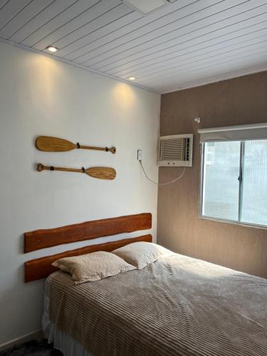 a bedroom with a bed and two wooden paddles on the wall at Casa paraíso dos milagres in São Miguel dos Milagres