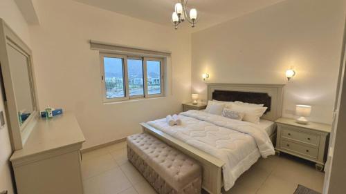 a bedroom with a large white bed with a window at Century Stay by Bait Zain in As Sīfah