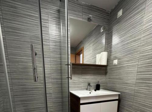 a bathroom with a sink and a shower with a mirror at Sošice Garden Apartments in Sošice