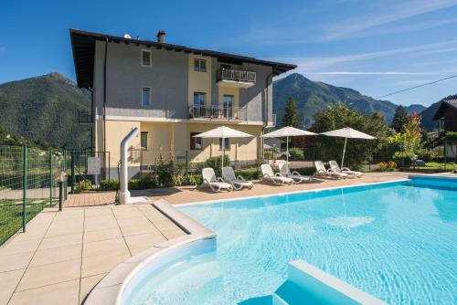 a villa with a swimming pool in front of a building at Recidence EMILIO in Ledro