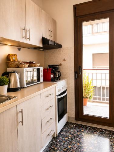a kitchen with a stove and a microwave and a window at Nickolas Sea View Apartment in Paleo Tsifliki
