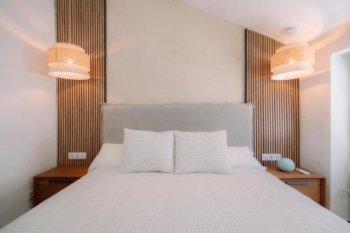 a bedroom with a white bed with two lamps at Casita Capricho in Zuheros