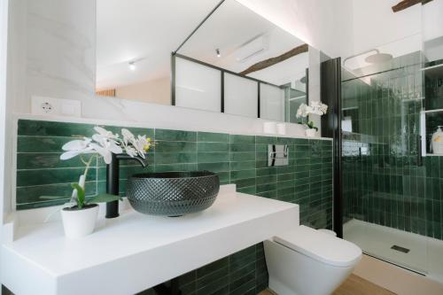 a bathroom with a toilet and a green tiled wall at Casita Capricho in Zuheros