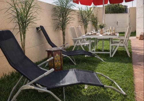 two chairs and a table in the grass with an umbrella at Azra Luxe villa famille uniquement Family only in Saïdia