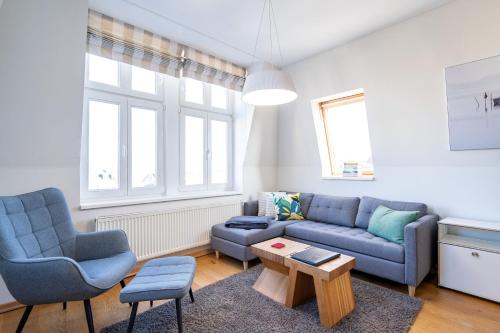 a living room with a blue couch and two chairs at Schloss am Meer App 5 in Ahlbeck