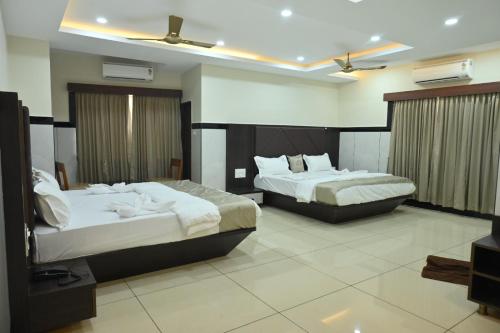 a hotel room with two beds and a television at Kamath Yatri Nivas Plus in Māvalli