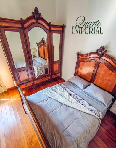 a bedroom with a bed and a large mirror at Refúgio Casarão in Passa Quatro