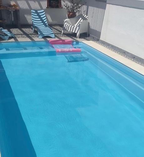 a swimming pool with two lawn chairs and a swimming pool at Morada da Vovó Alda in Almeirim