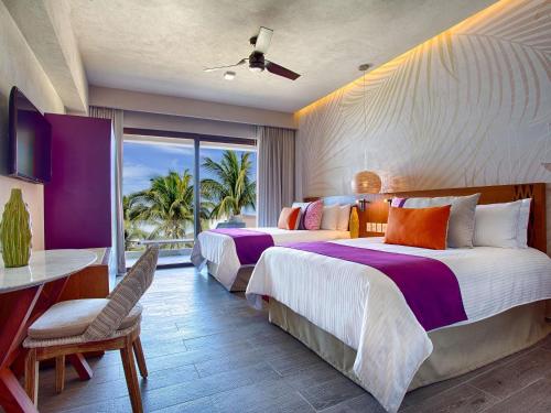 a hotel room with two beds and a balcony at Armony Marival Resort & Spa Punta de Mita - MGallery collection in Punta Mita