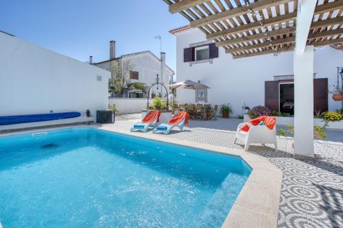 a swimming pool with chairs and a house at Morada da Vovó Alda in Almeirim