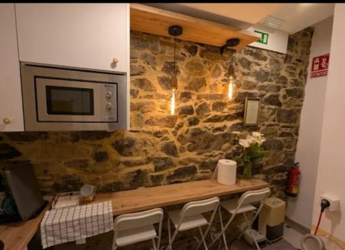 a kitchen with a stone wall with a table and chairs at Casa Magua Melide in Melide
