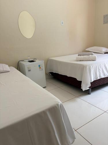 a room with two beds and a mirror on the wall at Vila Suítes in Barcarena