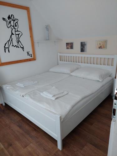 a white bed in a room with a picture on the wall at Anna-lak in Gyula