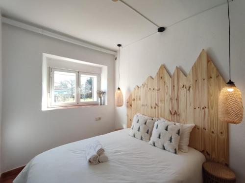 a bedroom with a white bed with a wooden headboard at El cielo de Béjar, casa rural in Béjar