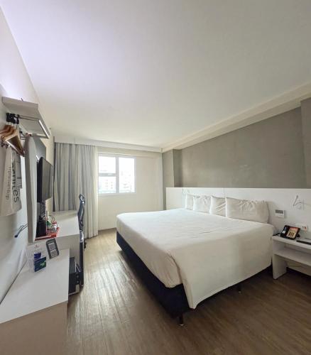 a hotel room with a large bed and a television at Esuites Virgínia Luxemburgo in Belo Horizonte