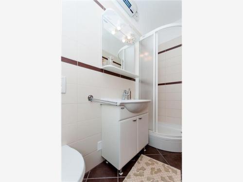 a white bathroom with a sink and a shower at Apartments Ruzmarin in Lun