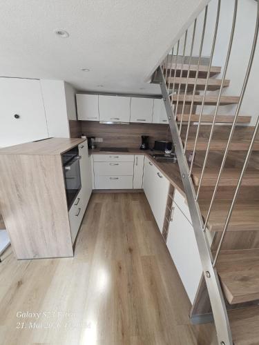 a kitchen with white cabinets and a staircase at Schneiders Apartment Style House in Trunkelsberg