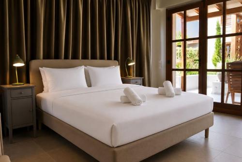 a bedroom with a large white bed and a window at Galetso Studios by Still Collection in Nikiti