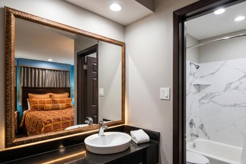 a bathroom with a mirror and a sink and a bed at Delux Inn Mesquite Near I-30 Dallas in Mesquite