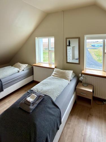 a bedroom with two beds and two windows at Guesthouse Vatnsholt in Vatnsholt