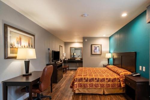 a hotel room with a bed and a desk at Delux Inn Mesquite Near I-30 Dallas in Mesquite