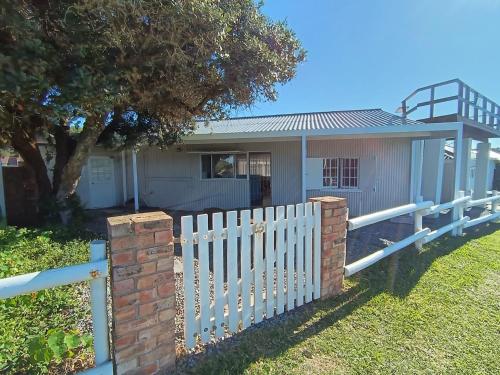 a white picket fence in front of a house at Kayser's Keep Self-Catering in Kayserʼs Beach