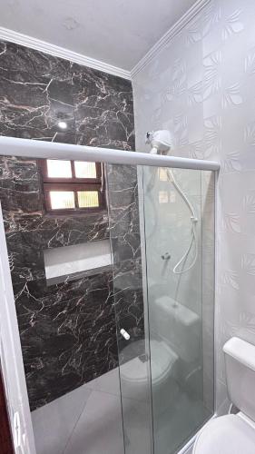 a bathroom with a glass shower with a toilet at Pousada Morena Raiz in Ubatuba