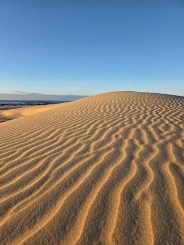 a sand dune with a blue sky in the background at Kayser's Keep Self-Catering in Kayserʼs Beach