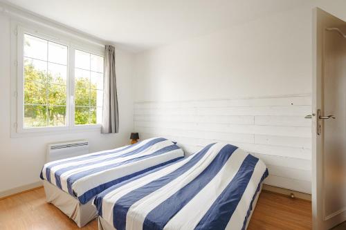 two beds in a room with white walls and a window at Cottage Chaleureux Proche Ocean in Salles-sur-Mer
