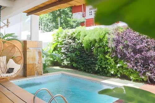 a swimming pool in a garden with purple flowers at Refugio de Luxo com Piscina e Jacuzzi em Pipa in Pipa