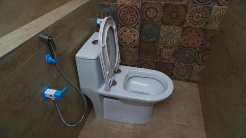 a white toilet in a bathroom with a hose at A One Residency in Nāgercoil