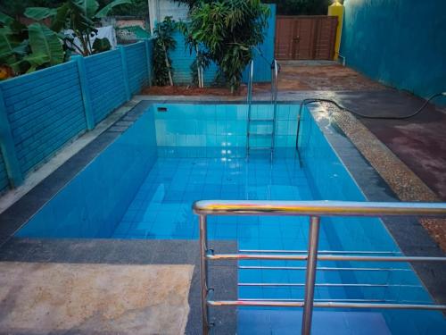 a blue swimming pool with a metal rail in it at D S Villa with swimming pool in Kuilapayam