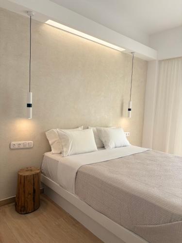 a bedroom with a large bed with two pendant lights at Hotel Faros in Ios Chora