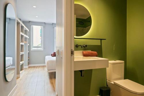 a green bathroom with a sink and a mirror at The Orbit Apartments in Barcelona
