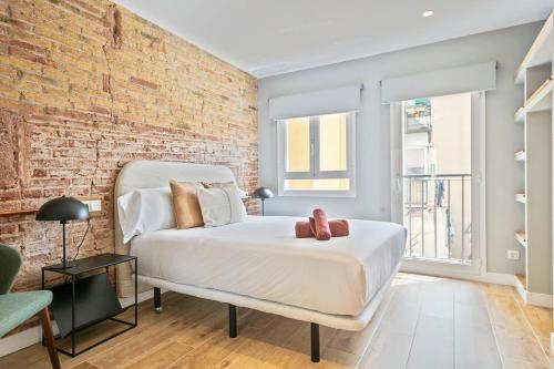 a bedroom with a white bed and a brick wall at The Orbit Apartments in Barcelona
