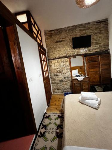 a bedroom with a bed in a room with a stone wall at Guest House Salaria in Gjirokastër