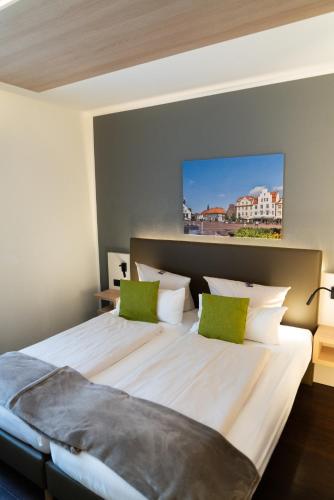 a bedroom with a large white bed with green pillows at Stadthotel im Kolpinghaus Lingen in Lingen
