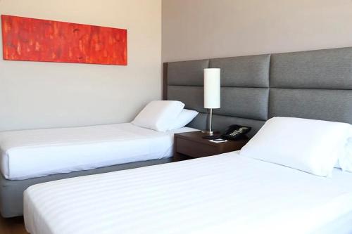 a hotel room with two beds and a lamp at Hotel Estelar El Cable in Manizales