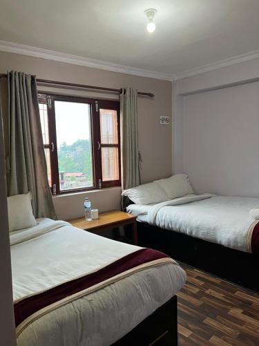 a hotel room with two beds and a window at Bandipur Samira Hotel & Homestay - your comfort in heart of Bandipur in Bandipur