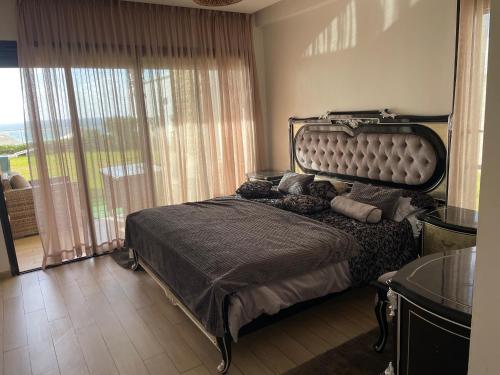 a bedroom with a large bed and a large window at OCEAN VIEW, Prestigia Plage des Nations in Sidi Bouqnadel