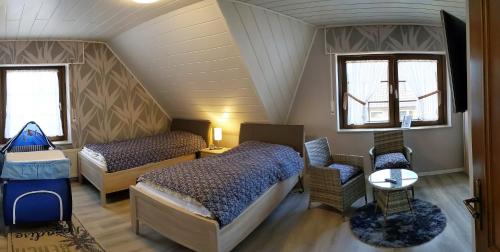 a bedroom with two beds and a chair in a attic at Haus Münsterland in Nordwalde