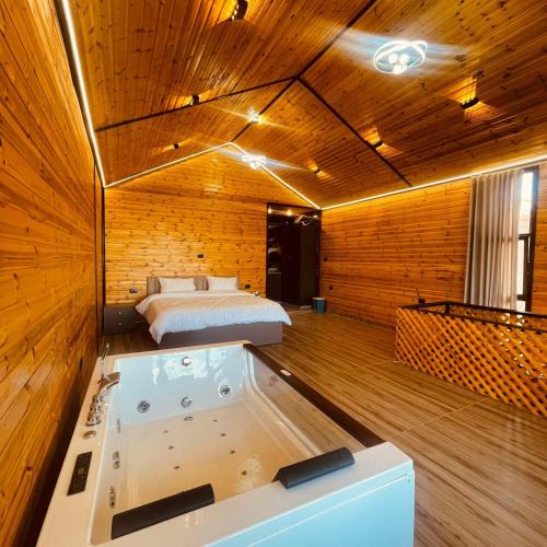 a bedroom with a tub and a bed in a room at اكواخ السوسنة السوداء in Ajloun
