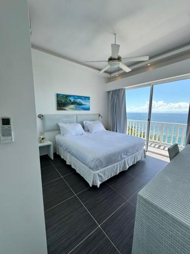 a white bedroom with a bed and a balcony at Vista Mare Samaná in Punta Balandra