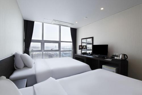a hotel room with two beds and a desk and a window at Hotel K-Tree Pyeongtaek in Pyeongtaek