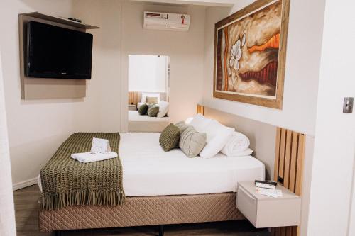 a hotel room with a bed and a tv at Hotel Daieli in Otacílio Costa