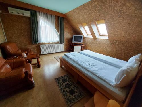 a bedroom with a bed and a chair and a television at Hotel Christine in Târgu Secuiesc