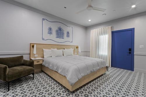 a bedroom with a bed and a chair and a blue door at Hotel Biloxi in Biloxi